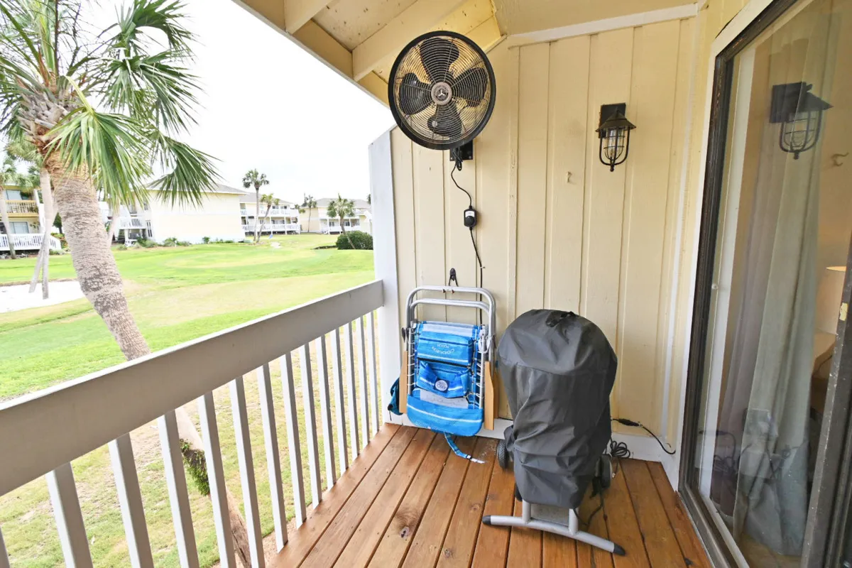 A private balcony overlooking a manicured lawn, with a comfortable beach chair and an outdoor fan. The space is casual and inviting, perfect for relaxing, enjoying the breeze, or sharing a quiet toast to the day’s adventures.