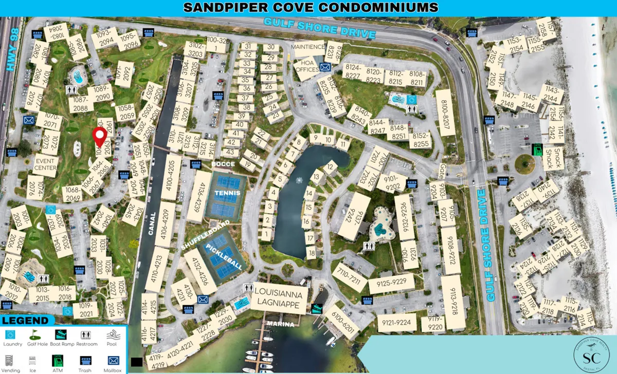 A wide aerial view encompassing the par-3 golf course with clearly marked holes, a marina with boat docks, several community swimming pools, and a cluster of tennis, pickleball, shuffleboard, and bocce ball courts. Condominium buildings frame the amenities, and the beach is visible nearby, emphasizing the proximity and integration of all resort-style features.
